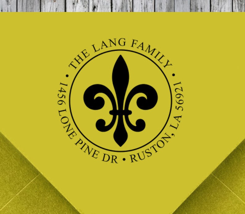 K&ouml;nnte beinhalten: Ein gelber R&uuml;cksendeaufkleber mit einem schwarzen Fleur-de-lis-Design. Der Text lautet "The Lang Family, 1456 Lone Pine Dr, Ruston, LA 56921."