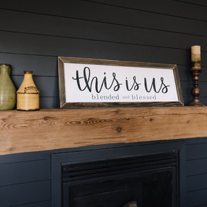 May include: A wooden mantel with a framed sign that reads "This is us, blended and blessed". There are two decorative vases and a candle holder on the mantel.