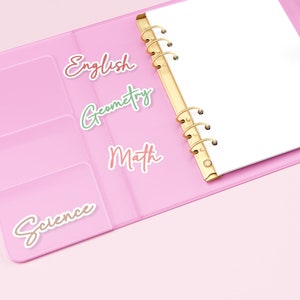 May include: A pink binder with gold rings, open to reveal a blank white page. Subject labels for English, Geometry, Math, and Science are placed on the left side. The background is a solid pink.