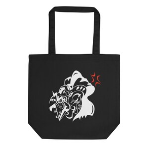 May include: Black tote bag with a white graphic design featuring a stylized illustration of a face with sharp angles and a red burst. The bag has two black handles and is made of a sturdy material.