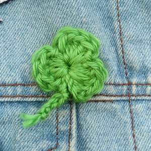 May include: A green crocheted shamrock pin on a blue denim jacket.