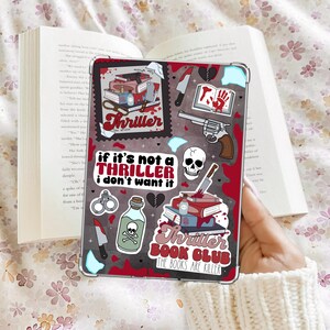 May include: A clear tablet case with a red and black design featuring the word "Thriller" and various illustrations. The case includes images of a skull, a revolver, knives, and the text "If it's not a thriller I don't want it."