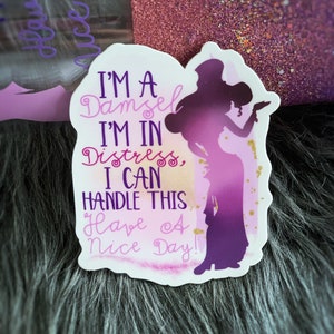 May include: A white sticker with a purple silhouette of a woman with a crown and the text "I'M A Damsel I'M IN Distress, I CAN HANDLE THIS Have A Nice Day!"