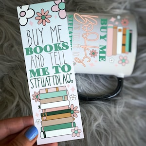 May include: A pink and green bookmark with a stack of books and the text "BUY ME BOOKS AND TELL ME TO STFUATTDLAGG".