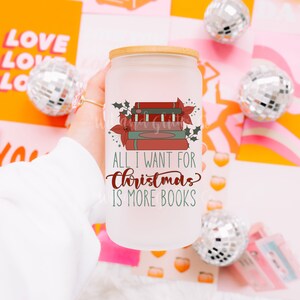 May include: A white frosted glass mug with a bamboo lid. The mug has a graphic of a stack of books with a red poinsettia and holly. The text reads "All I want for Christmas is more books".