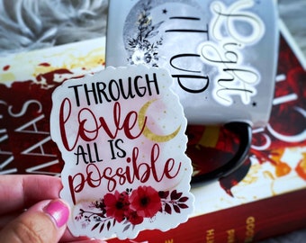 May include: A white sticker with a gold crescent moon and red flowers. The sticker says "Through love all is possible".