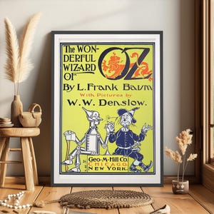 May include: A vintage poster advertising "The Wonderful Wizard of Oz" by L. Frank Baum, illustrated by W.W. Denslow. The poster features a yellow background with a large, stylized "OZ" in red and blue. The Tin Woodman and Scarecrow characters from the book are depicted in the lower portion of the poster.
