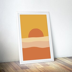 May include: Abstract sunset art print with a yellow, orange, and brown color scheme. The print features a large orange sun setting over a series of wavy lines.
