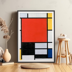 Puede incluir: Impresión artística enmarcada con un diseño geométrico abstracto. Presenta un gran cuadrado rojo, rectángulos negros, blancos, amarillos y azules. La obra de arte está en un marco negro. Un jarrón beige con plantas secas y un taburete de madera están en primer plano.