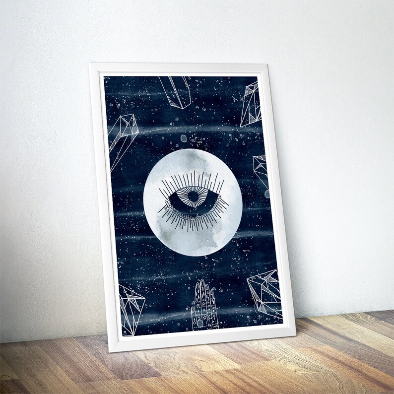 May include: A white framed print with a dark blue background featuring a white stylized eye inside a moon with white geometric shapes around it.
