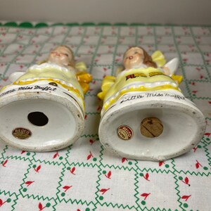 K&ouml;nnte beinhalten: Ein Paar vintage Salz- und Pfefferstreuer mit Little Miss Muffet. Die Streuer sind aus Keramik und in Gelb, Wei&szlig; und Rot bemalt. Auf der Unterseite jedes Streuers befindet sich ein Aufkleber mit der Aufschrift "Relco, Handcrafted, Japan".