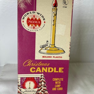 May include: A vintage Noma World Wide Decorative Lites Christmas candle in a box. The candle is made of molded plastic and is yellow with a red flame. The box is pink with white text and a picture of a fireplace with a lit candle.