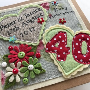 May include: A handmade Ruby Anniversary card with felt decorations. Features a heart with the names "Peter & Janice" and the date "27th August 2017". Includes a "40" in red with white polka dots, and felt flowers with button centres.