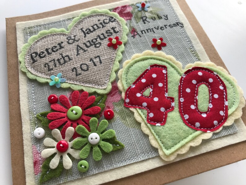 May include: A handmade Ruby Anniversary card with felt decorations. Features a heart with the names "Peter & Janice" and the date "27th August 2017". Includes a "40" in red with white polka dots, and felt flowers with button centres.