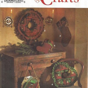 Op de afbeelding: Simplicity Crafts patroon met kerstthema ambachten. De afbeelding toont een verscheidenheid aan items, waaronder een krans, een kous, een hartvormig kussen en een tas, allemaal met een rood en groen geruit ontwerp. Het patroon is gelabeld "8159, ONE SIZE".