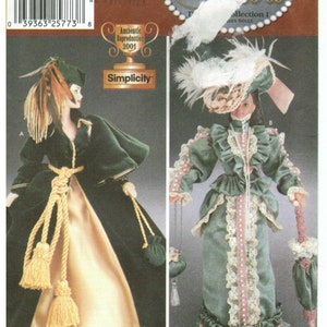 May include: Simplicity pattern 7213 for a Diva Collection doll. The pattern includes two outfits: a green velvet dress with a gold rope belt and a green dress with lace trim and a pink sash.
