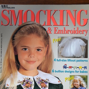 May include: A magazine cover for "Smocking & Embroidery" featuring a young girl wearing a green smocked dress with a white embroidered collar. The cover also includes a free pattern for a white smocked dress, 4 full-size liftout patterns, 6 bullion designs for babies, 14 smocking designs for all ages, and a chance to win a sewing room.