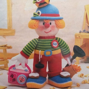 Könnte beinhalten: Eine Strickanleitung für eine Clown-Puppe, die einen blauen Hut mit einem Hamburger obenauf trägt, ein rot-grünes gestreiftes Hemd, rote Hosen und blaue Schuhe. Die Puppe hält einen Kolben und ein rosa Radio. Das Muster ist betitelt "Jean Greenhowe's Tradesmen Clowns - The Red Nose Gang - Part Four!" und wird mit Doppelstrickgarn hergestellt.