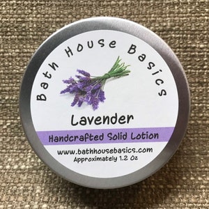 May include: A silver tin with a white label that reads "Bath House Basics Lavender Handcrafted Solid Lotion www.bathhousebasics.com Approximately 1.2 oz". The label also features a sprig of lavender.