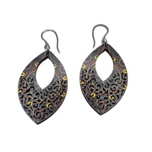 Pode incluir: Um par de brincos pendentes com fundo cinza, preto e branco. Os brincos têm um padrão floral com detalhes amarelos, laranja e vermelhos. Os brincos são feitos de madeira e têm um gancho prateado.
