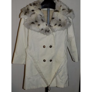 May include: A white coat with a large, fluffy, black and white fur collar. The coat has a double breasted closure and a belt.