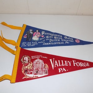 May include: Two vintage felt pennant flags. The blue flag reads "Pennsylvania Dutch Gift Haus Heart of the Dutch Country, Shartlesville, PA." The red flag reads "Washington Memorial Chapel, Valley Forge, PA."