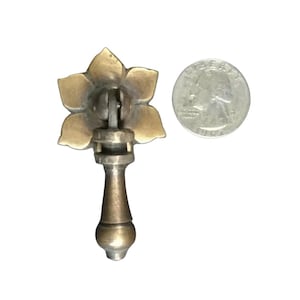 以下が含まれることがあります： 花柄の真鍮製のキャビネットプル。プルは25セント硬貨と同じくらいの大きさです。