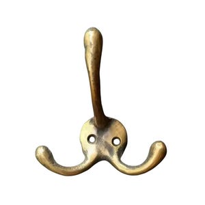 May include: A brass triple hook with a curved design. The hook is a solid piece of metal with a smooth finish.