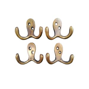 May include: Four brass double hooks in the shape of an octopus. Each hook has two prongs and a circular base.