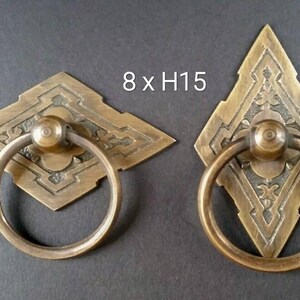 May include: Two ornate brass door pulls with a diamond-shaped design and a ring handle. The pulls are 8 inches wide and 15 inches high.