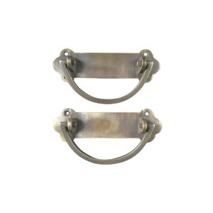 May include: Two antique brass drawer pulls with a rectangular plate and a curved handle. The pulls have a distressed finish and are perfect for adding a vintage touch to any furniture.