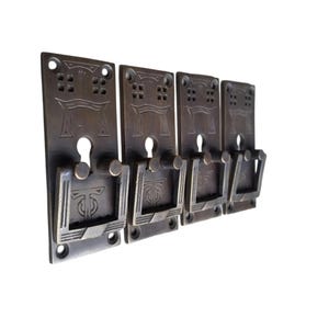 May include: Set of four antique bronze-toned cabinet pulls. Each pull features a rectangular backplate with decorative cutouts and a keyhole. The handles have a geometric design. The pulls are mounted on a white background.