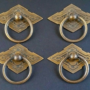 Könnte beinhalten: Vier antike Messing-Schranktürgriffe mit verzierten rautenförmigen Platten und Ringgriffen.