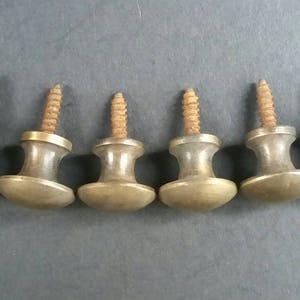 May include: Six antique brass cabinet knobs with screws. The knobs are round and have a slightly domed top. They are all in good condition with some signs of wear.