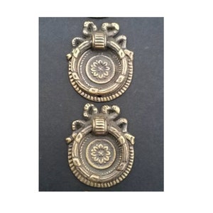 May include: Two antique brass drawer pulls with a ring handle and a decorative floral design.