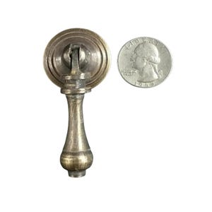 Könnte beinhalten: Ein Messing-Schrankgriff mit runder Basis und einem geriffelten, sich verjüngenden Griff. Der Griff ist etwa so groß wie eine deutsche 2-Euro-Münze.