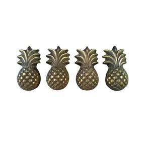 May include: Four gold pineapple-shaped drawer pulls. The pineapple design is detailed and realistic.