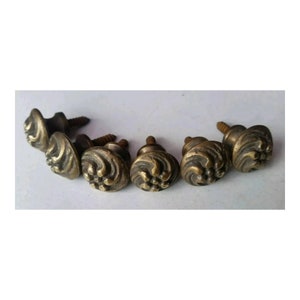 May include: Six antique brass cabinet knobs with ornate floral designs and screws.