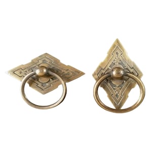 May include: Two antique brass door pulls with ornate diamond-shaped plates and ring handles.