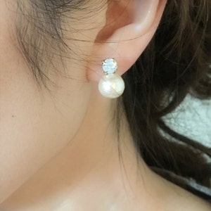 May include: A pair of gold earrings with a white pearl and a clear rhinestone.
