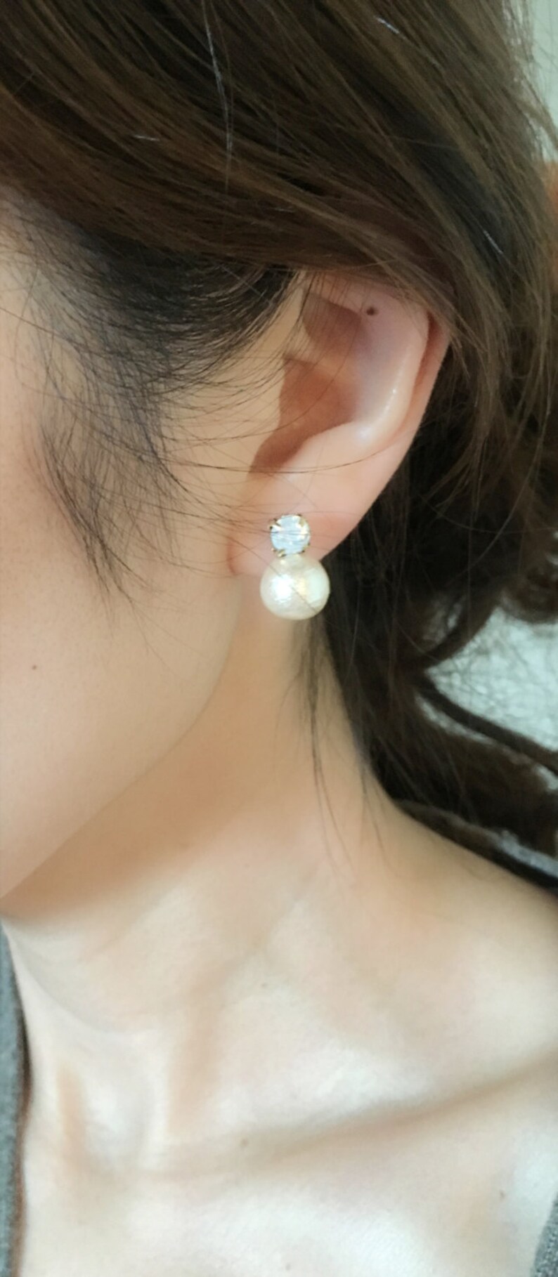 May include: A pair of gold earrings with a white pearl and a clear rhinestone.