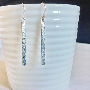 May include: A pair of silver hammered bar earrings with a simple hook closure.