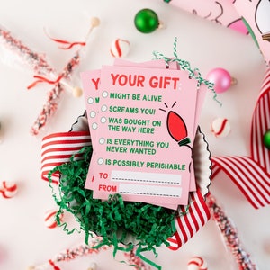 May include: Pink gift tags with a red lightbulb graphic and the text "Your Gift" and a checklist of humorous gift descriptions. The text includes "Might be alive", "Screams you!" and "Is possibly perishable".