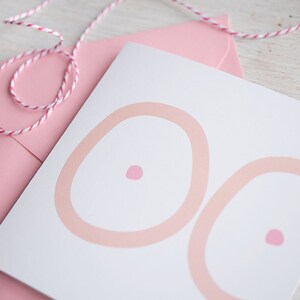 May include: A white card with two pink circles, each with a smaller pink circle in the center. The card is sitting on a pink envelope.