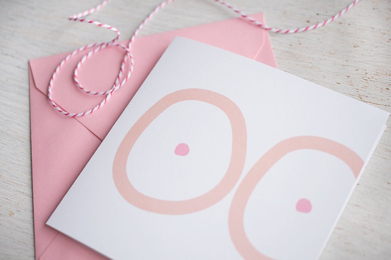 May include: A white card with two pink circles, each with a smaller pink circle in the center. The card is sitting on a pink envelope.
