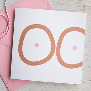May include: A white card with two brown circles and pink dots in the center of each circle. The card is sitting on a pink envelope.