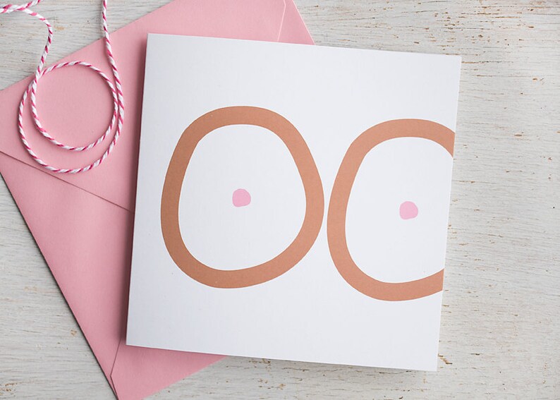 May include: A white card with two brown circles and pink dots in the center of each circle. The card is sitting on a pink envelope.