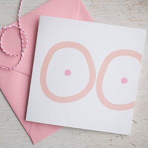 May include: A white card with two pink circles, each with a smaller pink circle in the center. The card is sitting on a pink envelope.