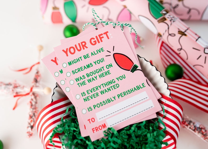 May include: Pink gift tags with a green and white checklist that says "Your Gift: Might be alive, Screams you!, Was bought on the way here, Is everything you never wanted, Is possibly perishable."  The tags have a red lightbulb illustration and spaces to write "To" and "From".
