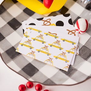 May include: A set of three gift tags with a yellow taxi cab pattern. The cabs have a pretzel on top and the text "I  <3  NY" on the side. The tags are on a black and white checkered surface.